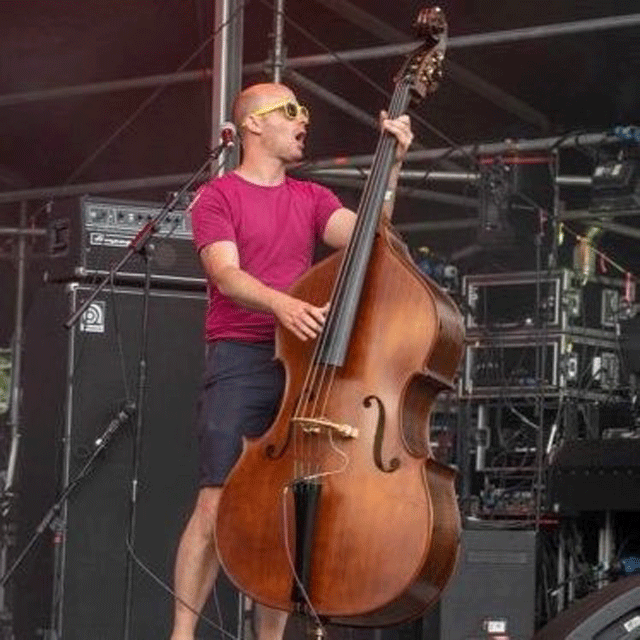 Andrew wearing pink t-shirt and shorts, playing double bass