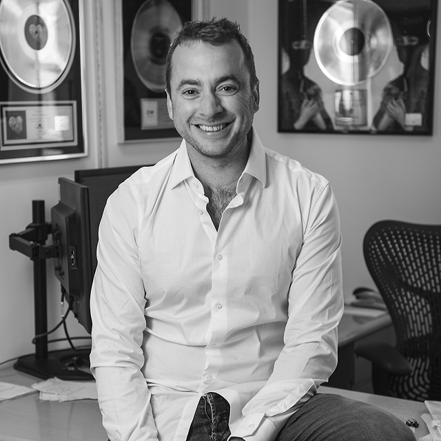 Black and white photo of Berkeley sitting on a desk with gold records on wall