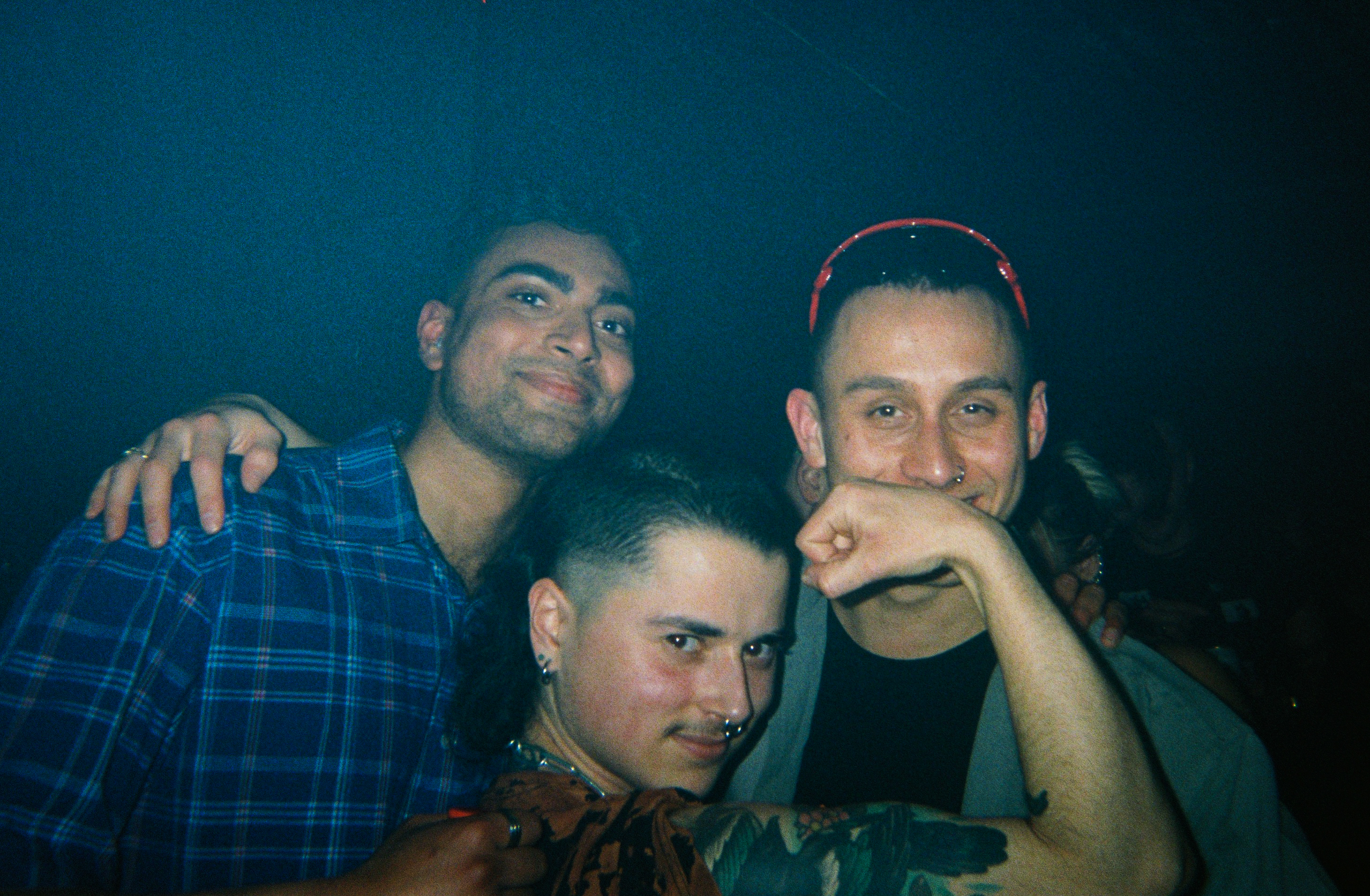 three people pose for a photo in a nightclub