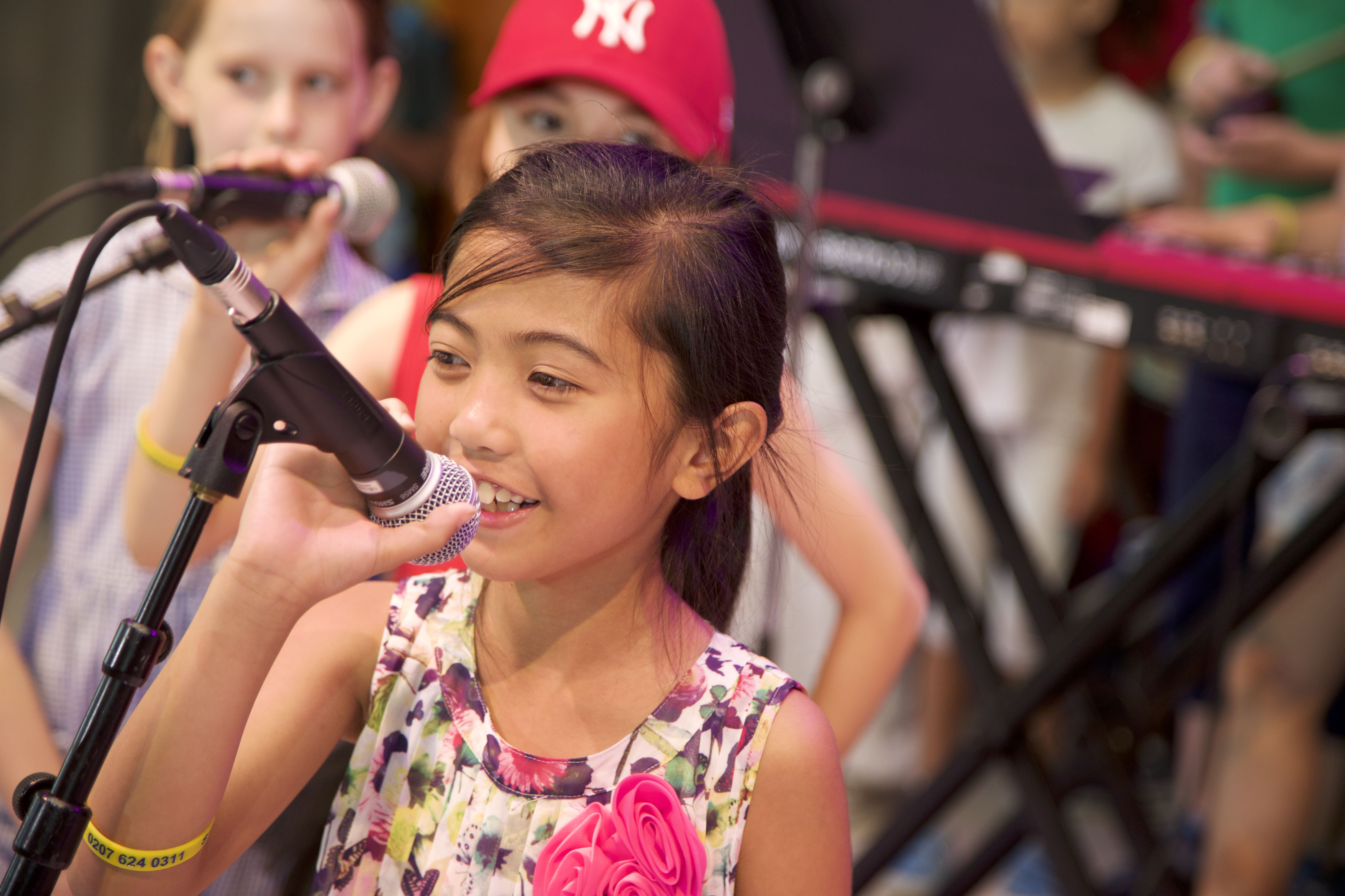 a young girl sings into a microphone