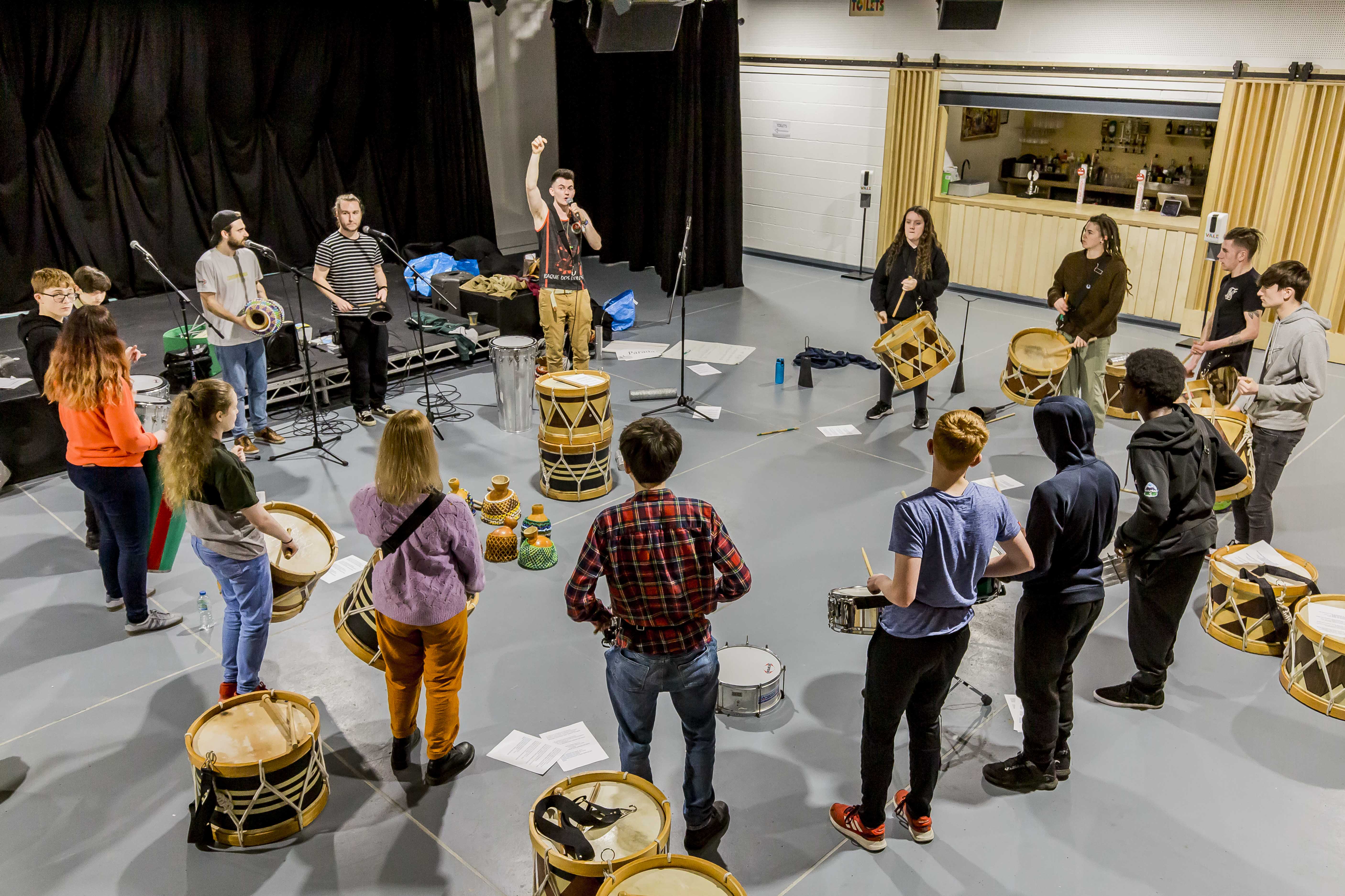 a group of young people stand in a circle with drums
