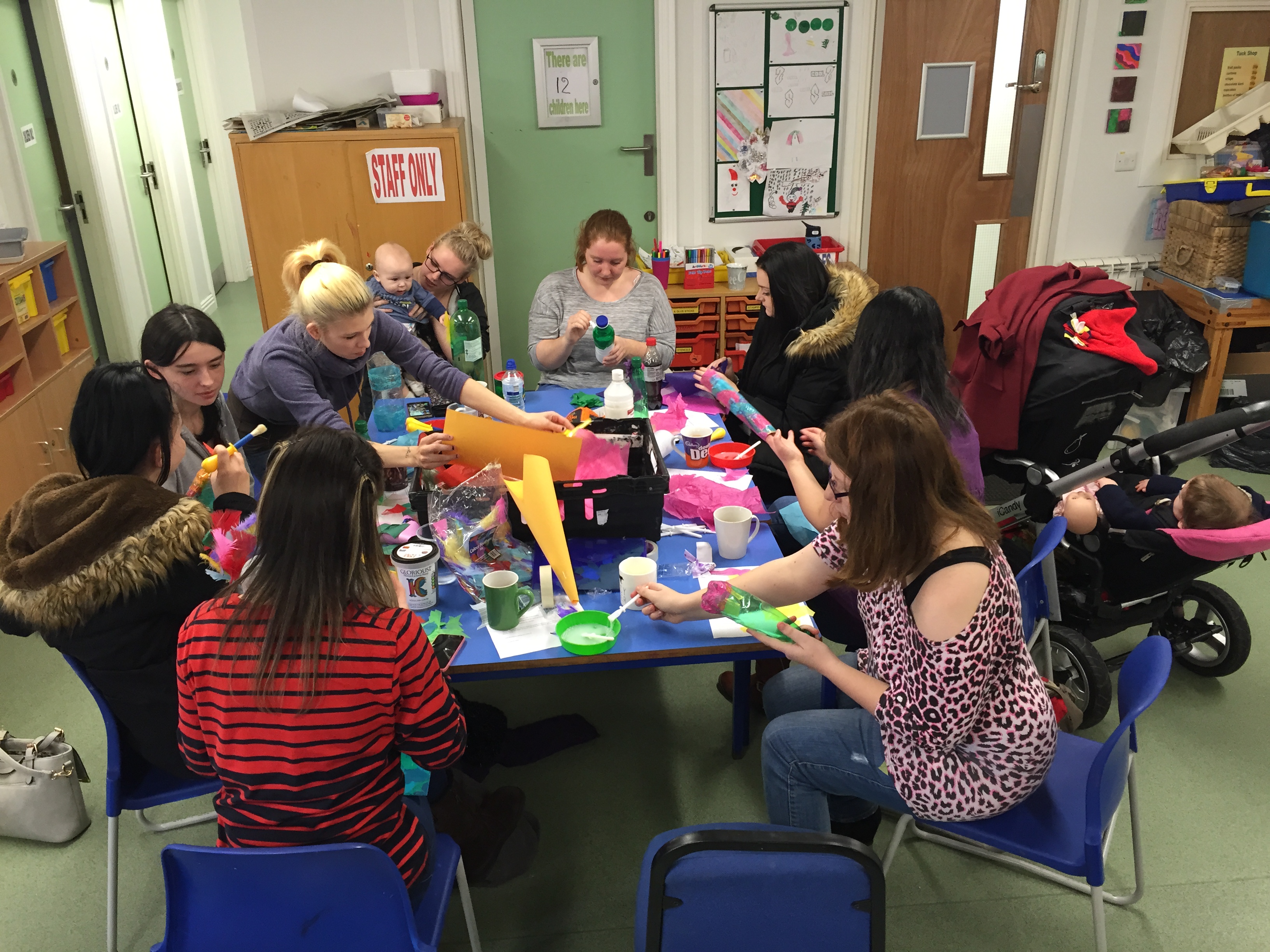 a group of women make instruments with babies around a table