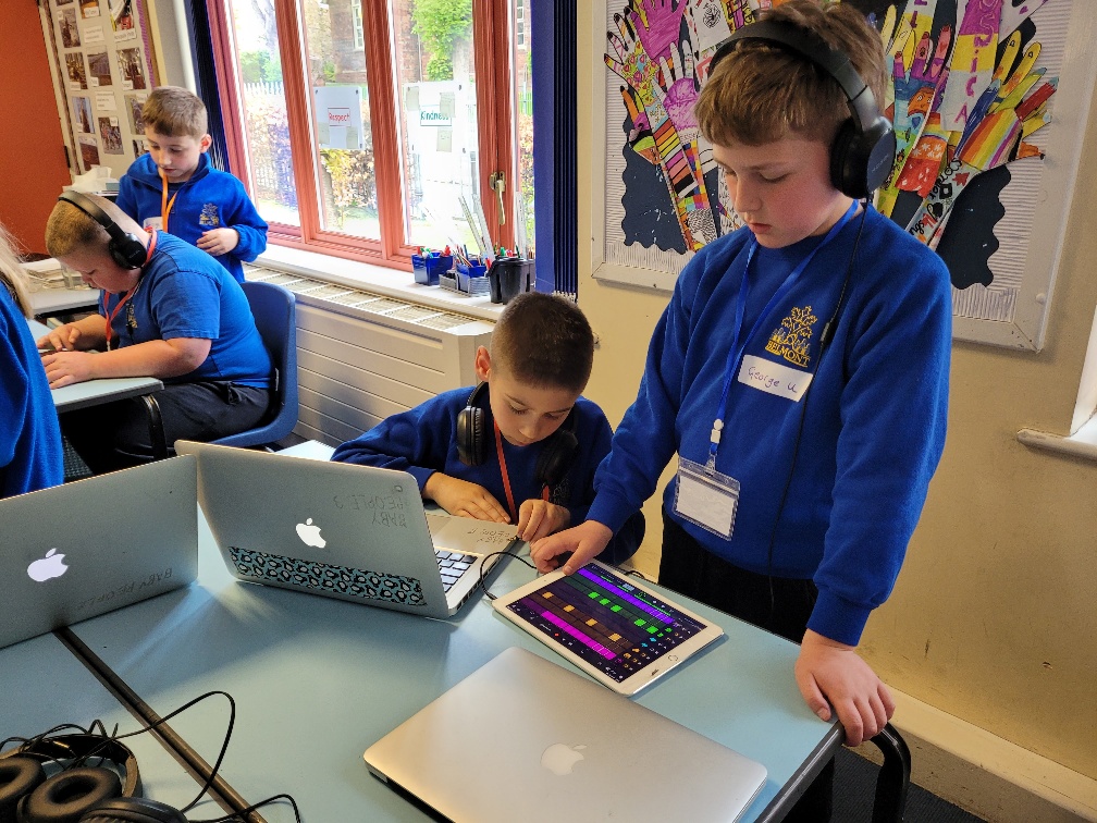 two boys play with ipads to make digital music in a classroom