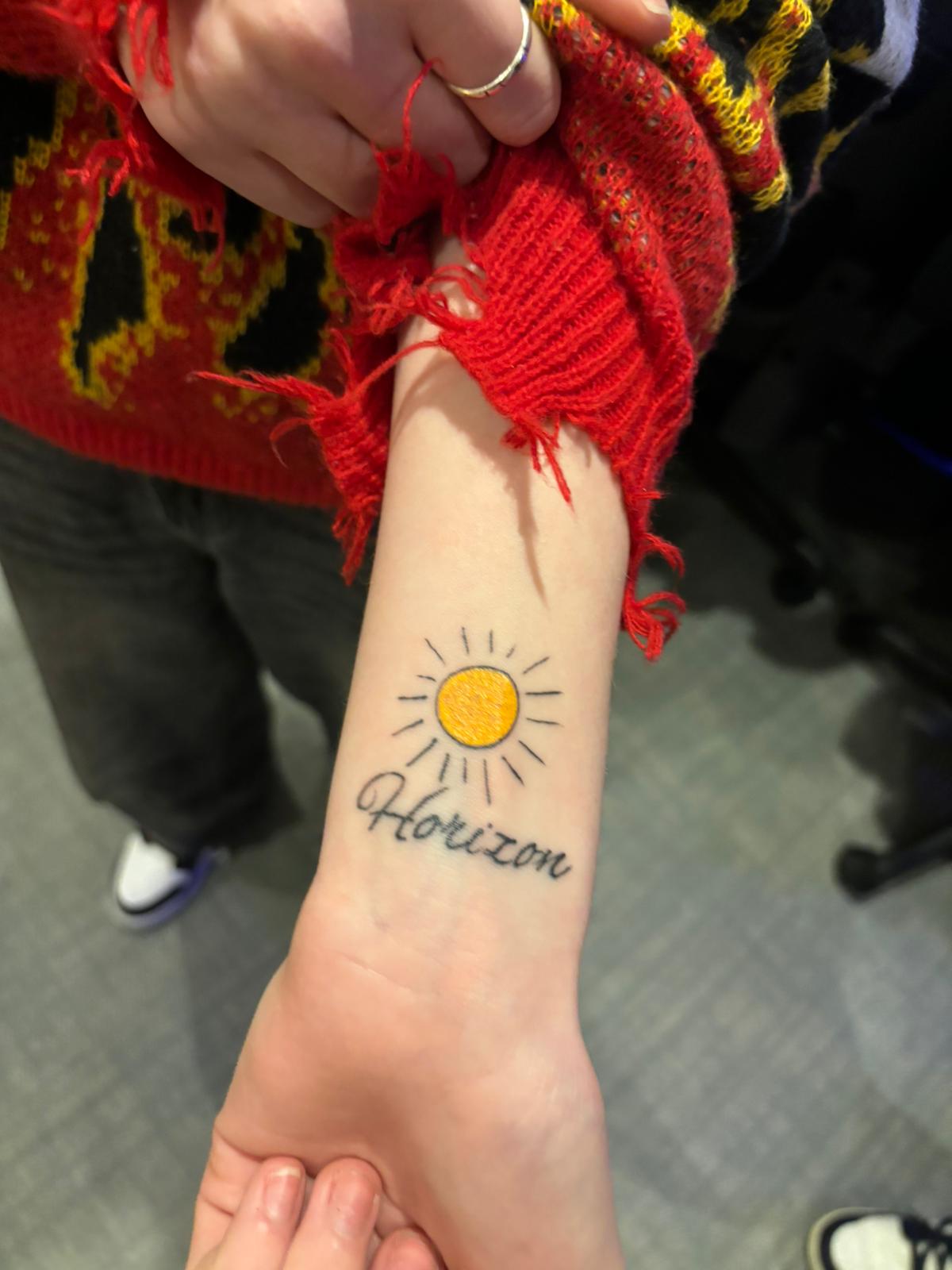 a sun tattoo on a forearm