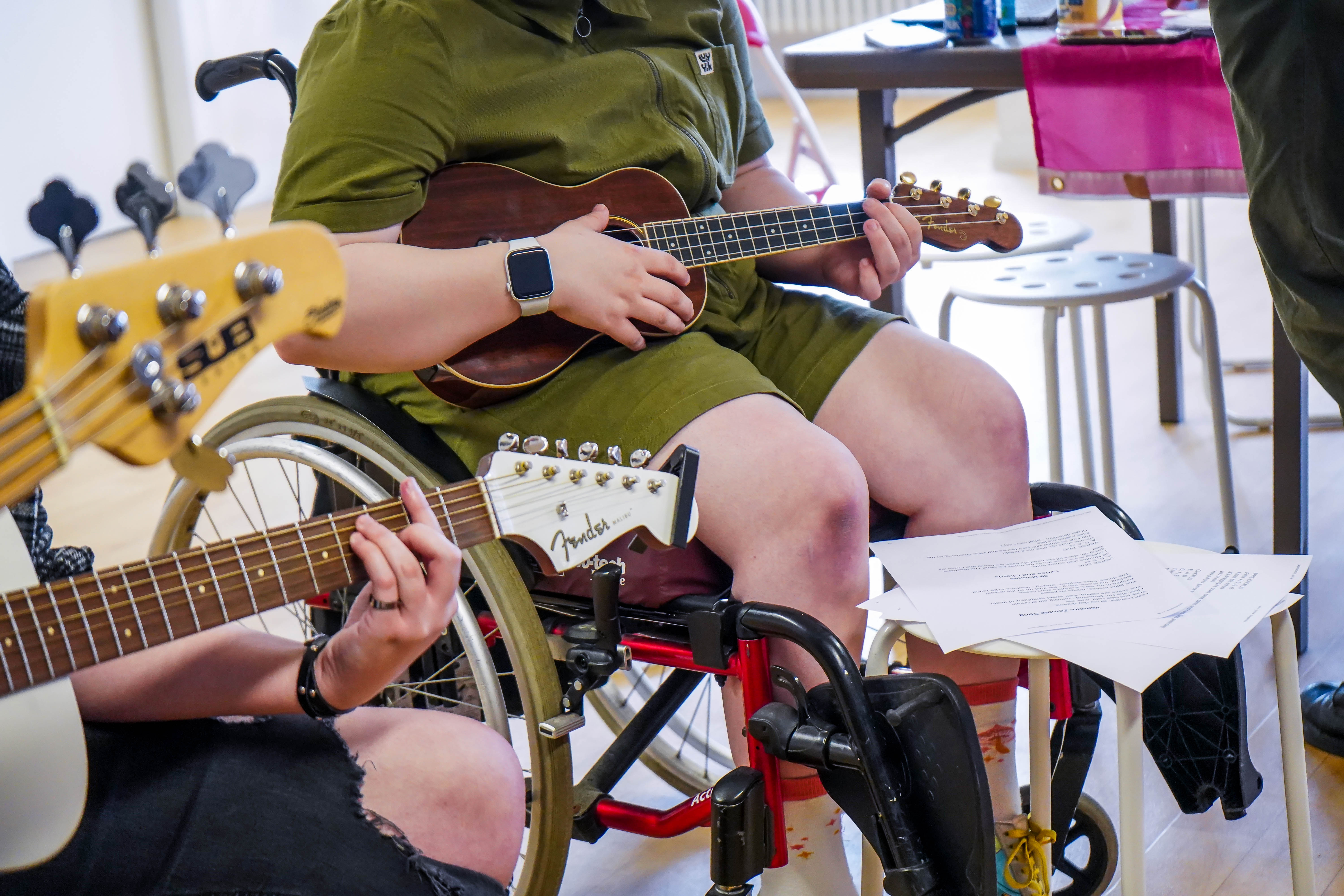 a young person in a wheelchair plays a ukelel