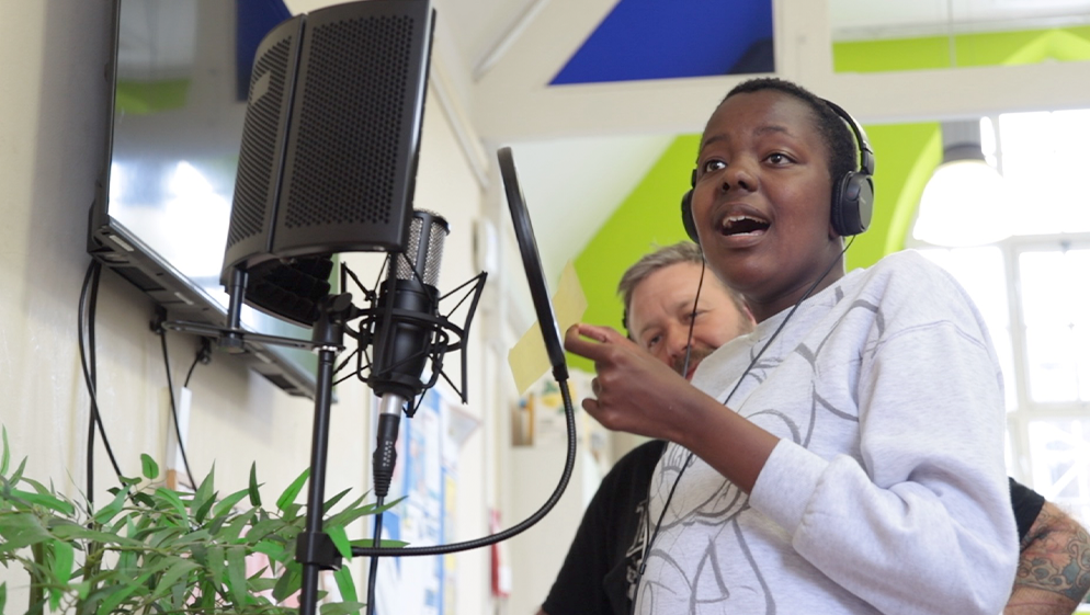 a young person wears headphones and sings into a recording device