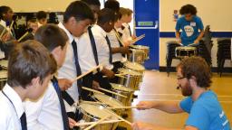 A dozen school kids drumming in the Exchanging Notes programme