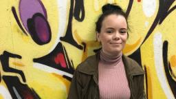 Molly standing in front of a graffiti wall 