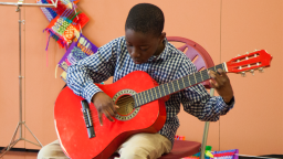young musician playing a red guitar