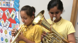 Aisha (left, with trumpet), and Isma (right, with baritone) playing their instruments in school