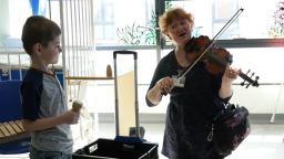 Sarah playing the violin and a boy plays with a shaker in hospital