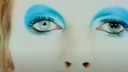 close up of two eyes and a nose, the eyes have bright blue eyeshadow and ginger hair is visible on the left side.