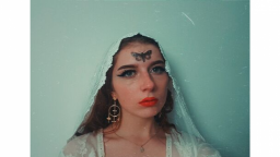 Woman wearing white lace veil with moth tattoo on forehead