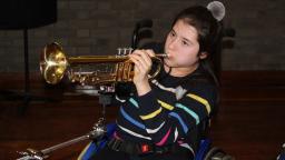 a girl in a wheelchair plays the trumpet