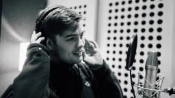 boy wears headphones in front of a microphone in a studio