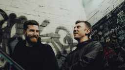Photo of Electronic Duo Bicep smiling on a stairway with graffiti in the background
