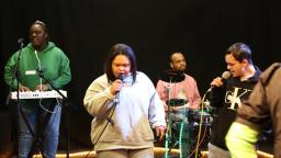a group of young people with learning disabilities sing and play instruments together.
