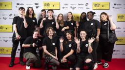 a group of young people pose on the red carpet at the youth music awards 2022. they are wearing black t-shirts with the youth music logo
