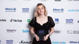eva davies holds her youth music award trophy, wearing a black dress.