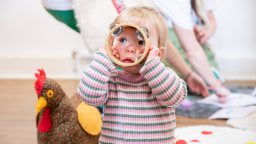 a baby wears a striped long sleeve top and holds a tambourine up to their face