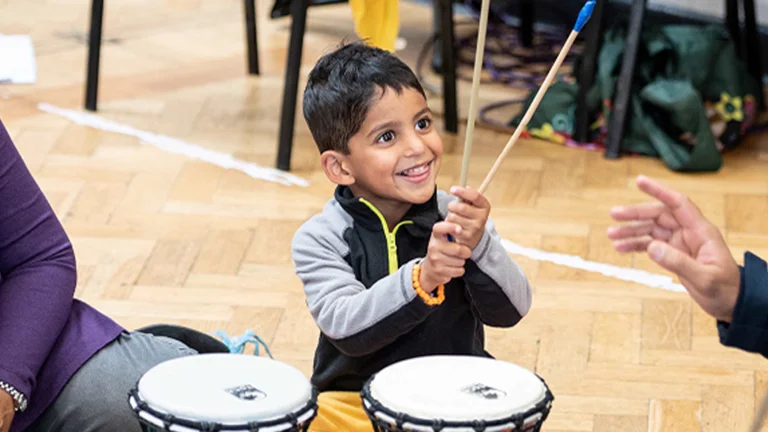 Young boy playing the drums with 2 adults