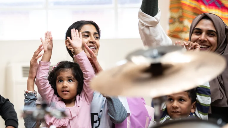 mums and toddlers raise their hands in the air