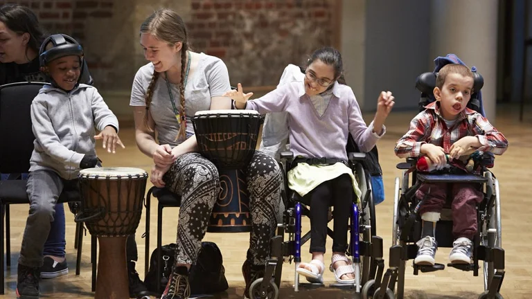 Disabled young people playing with instruments with a music leader. 