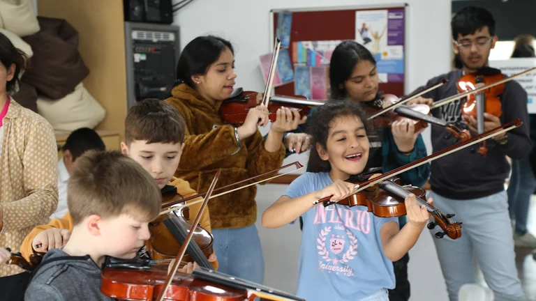 a group of children play violins in a classroom