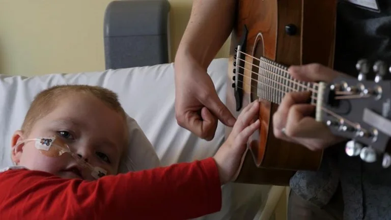 patient on bed strumming guitar with nick