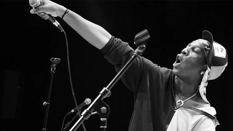 a young man with a cap holds a microphone up