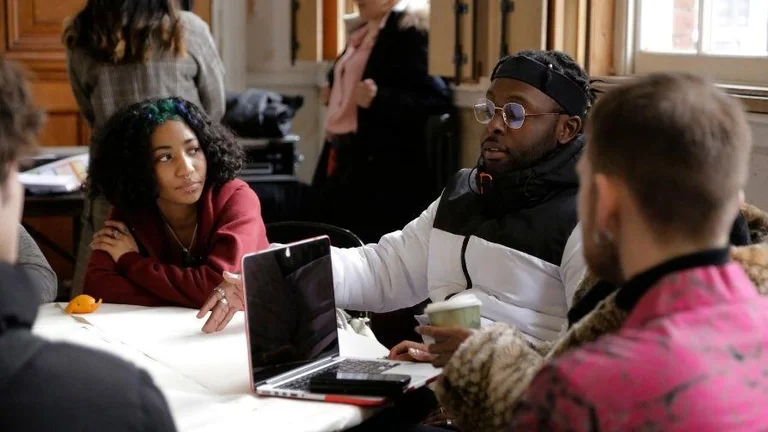 Some young people gather around a laptop, working and planning