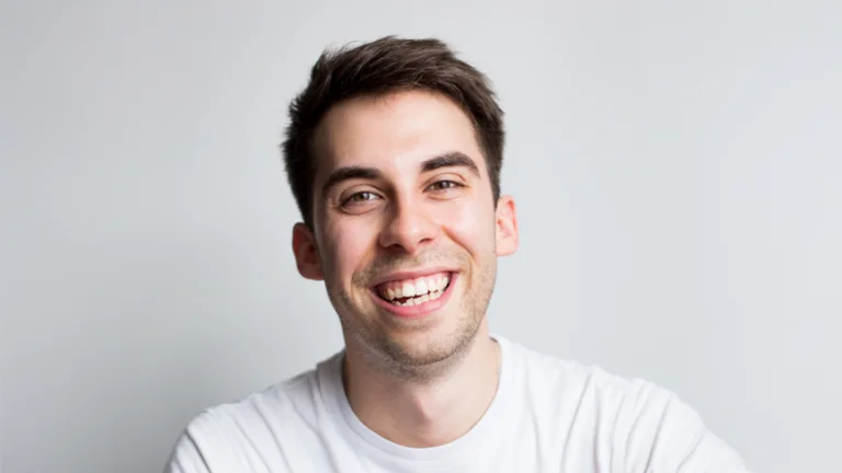 close up headshot, dark short hair, smiling in a white t-shirt