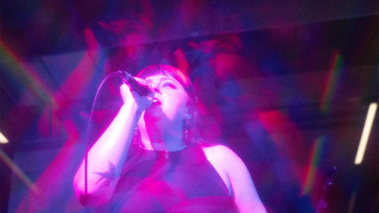 Woman singing on stage, purple lights all around her