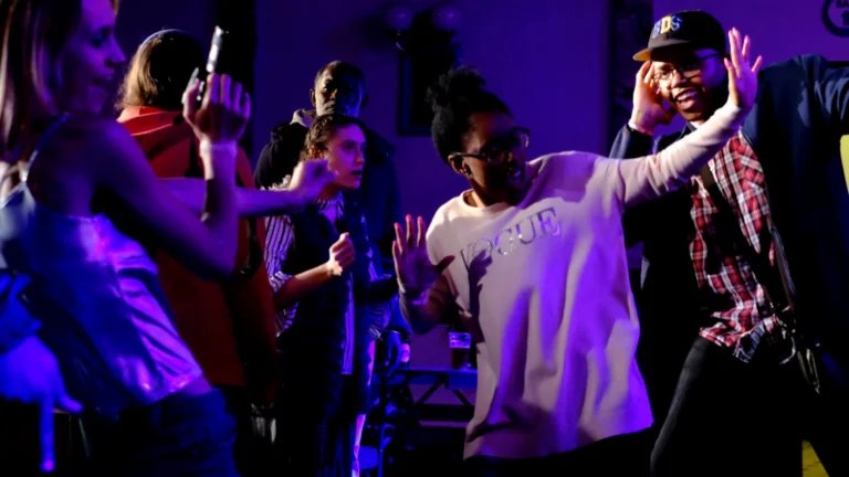 A group of six people of different ethnicities dancing and laughing in a dance floor. 