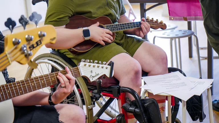 young person in wheelchair playing the ukulele