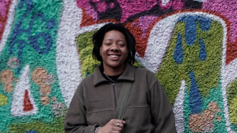 a person smiles and poses against a graffiti wall