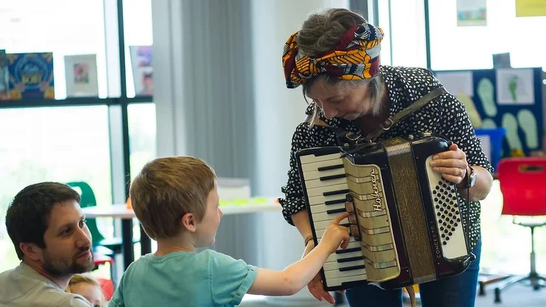 Woman with a keyboard accordion with a child smiling and pressing the keys