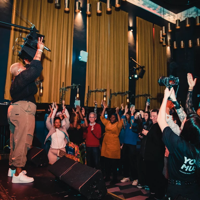 hamzaa raises her hands on stage and everyone in the audience does the same