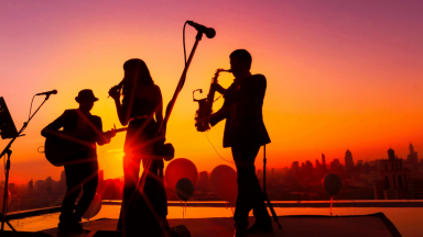 Three musicians silhoutted against a sunset