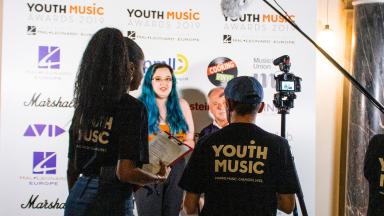 Two people wearing Youth Music t-shirts with backs to the camera.