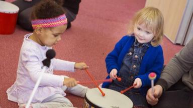 two young children banging drums