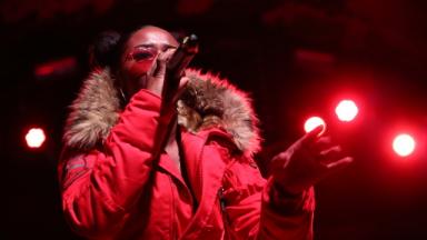 Nadia Rose in a red jacket performing on stage