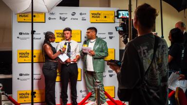 two presenters interview a winner on the red carpet