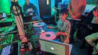 a young boy learning how to use DJ decks and software
