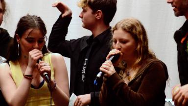two teenage girls clutch microphones