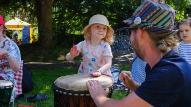 A child playing a drum in a park