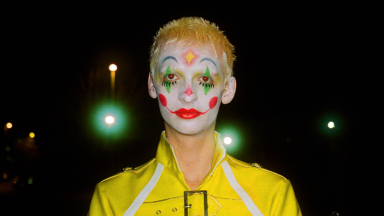 a person wears a yellow jacket and clown make up