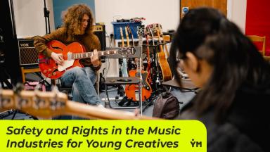 two people play guitars in a music room. the title of the web page is written on a yellow banner