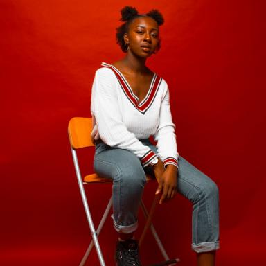 Young person sitting on a chair against a red background