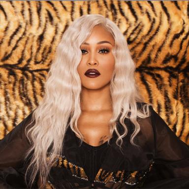 woman with white hair wearing black shirt, in front of a tiger print background